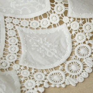 May include: White lace trim with a delicate floral pattern. The lace has a scalloped edge and is perfect for adding a touch of elegance to any project.