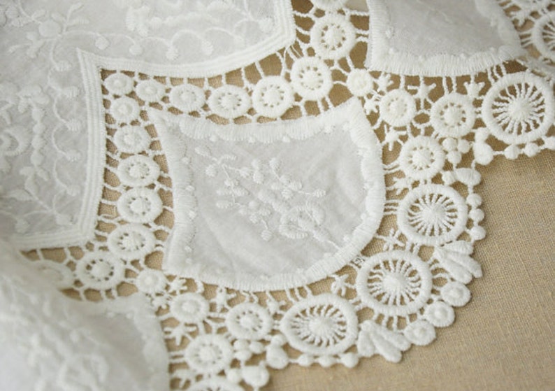May include: White lace trim with a delicate floral pattern. The lace has a scalloped edge and is perfect for adding a touch of elegance to any project.