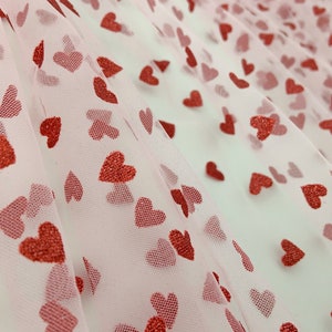 May include: Pink tulle fabric with a red glitter heart pattern.