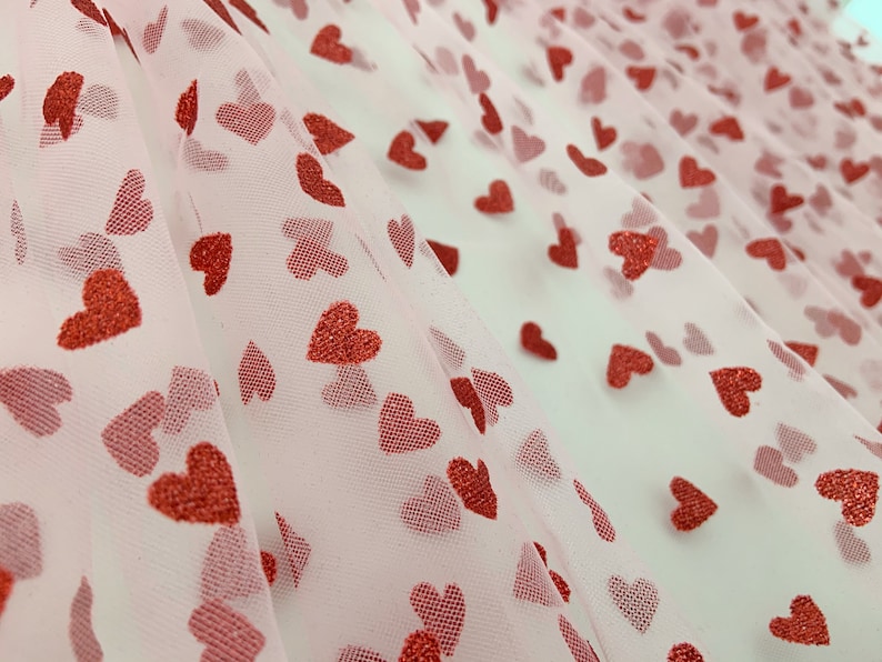 May include: Pink tulle fabric with a red glitter heart pattern.