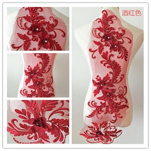 May include: Red lace applique with floral designs and pearl embellishments. The applique is on a sheer mesh fabric.