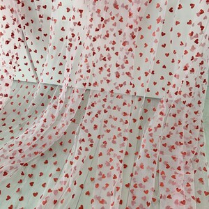 May include: Pink tulle fabric with red glitter hearts printed all over.