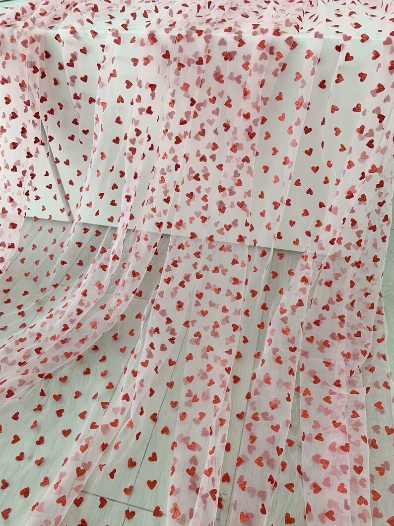 May include: Pink tulle fabric with red glitter hearts printed all over.