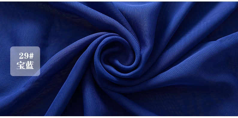 Puede incluir: Primer plano de una tela azul real con una textura suave y fluida. La tela est&aacute; doblada y drapeada, mostrando su ca&iacute;da y brillo. El texto "29#  宝蓝" es visible en la esquina superior izquierda de la imagen.