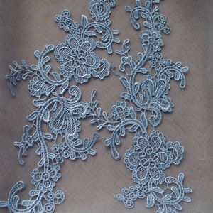 May include: Light blue lace applique featuring a floral design. The lace is delicate and intricate, with a variety of different shapes and sizes of flowers.