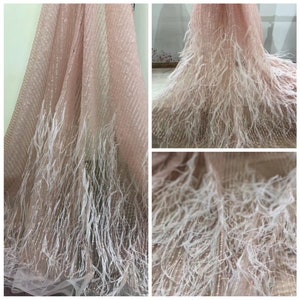 Puede incluir: Tela de tul rosa con ribete de plumas blancas. La tela tiene un brillo sutil y es perfecta para agregar un toque de elegancia a cualquier proyecto.