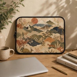 May include: A rectangular laptop sleeve featuring a detailed illustration of Mount Fuji, a flying crane, a deer, and a fox amidst stylized clouds, cherry blossoms, and pine trees in a muted color palette with a black zippered border.