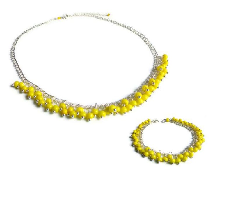 May include: A set of yellow beaded jewelry, including a necklace and a bracelet. Both pieces feature a delicate silver chain with small yellow beads hanging from it.