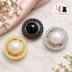 May include: Three circular decorative buttons featuring a central faux pearl or black stone, surrounded by a metallic lattice frame and an outer ring of small clear or black crystals. The buttons are gold, silver, and black metal finishes.