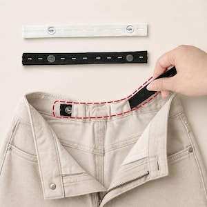 May include: Two adjustable elastic waistband extenders, one white and one black, each featuring two buttons and multiple buttonholes. The black extender is shown being attached to the interior waistband of a pair of light beige denim pants.