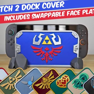 Może przedstawiać: Niebieska osłona stacji dokującej Nintendo Switch z centralnym żółtym symbolem Triforce i czerwonym herbem. Zestaw zawiera wiele wymiennych prostokątnych paneli przednich z różnymi kolorowymi wzorami, w tym symbolami takimi jak serce, oko i skrzydła.