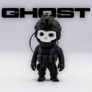 Op de afbeelding: Een zwart-witte sleutelhangerfiguur van een soldaat met een schedelmasker, tactische helm met nachtkijker en een vest met een Union Jack-patch. Het woord GHOST staat in dikke, zwarte hoofdletters boven de figuur afgebeeld.