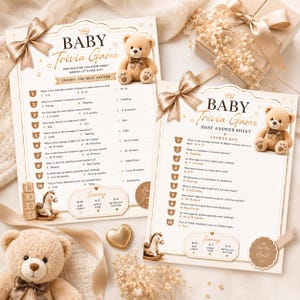 May include: Two printed baby trivia game cards with gold foil accents, featuring a teddy bear illustration, a list of ten questions, and a scoring section. The cards are decorated with a satin ribbon bow and a small rocking horse graphic.