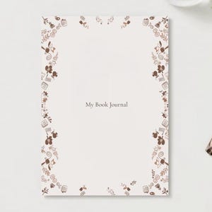 Könnte beinhalten: Ein rechteckiges Journal mit einem hellcremefarbenen Einband und einem braunen Rand aus botanischen Motiven und Büchern. Der Text My Book Journal ist mittig in einer dunkelbraunen Serifenschrift gedruckt. Das Design enthält kleine Blätter.