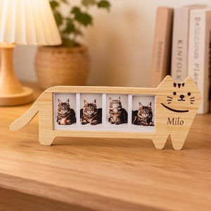 May include: A light-colored wooden cat-shaped picture frame featuring four rectangular photo slots. The frame displays four images of a brown tabby cat and includes the engraved name Milo on the right side, along with a simple cat face design.