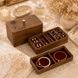 May include: A dark wood jewelry box with a lid featuring a laser-engraved flower and the name Sophia. The box includes a removable tray with compartments for rings and earrings, and a bottom tray lined with dark red velvet for bracelets.