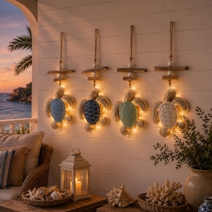 May include: Four wall-mounted sea turtle decorations hanging from wooden bars with attached string lights. Each turtle features a distinct shell colour: light blue, dark blue, seafoam green, and white. The turtles are illuminated by warm LED lights.
