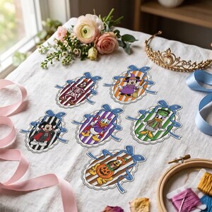 May include: Six oval-shaped paper cutouts featuring Disney characters in Halloween costumes, each framed by a blue ribbon bow. The characters include a skeleton, a witch, a vampire, a devil, a monster, and a pumpkin-themed dog on striped backgrounds.