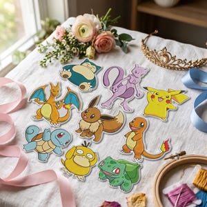 May include: A collection of nine embroidered patches featuring various colourful cartoon creatures including a yellow electric mouse, a blue turtle, an orange dragon, a brown fox-like animal, a green plant creature, and a purple psychic being.
