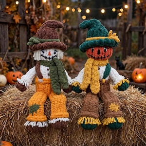 Puede incluir: Dos muñecos espantapájaros de ganchillo hechos a mano sentados uno al lado del otro. El muñeco de la izquierda tiene un sombrero marrón, cara blanca y peto naranja. El de la derecha tiene sombrero verde, cabeza de calabaza naranja y peto marrón.