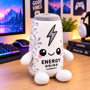 May include: A plush toy shaped like an energy drink can, featuring a white body with grey floral patterns, a grey top, and two small arms and legs. The front displays a black lightning bolt, a smiling face with pink cheeks, and the text ENERGY DRINK.