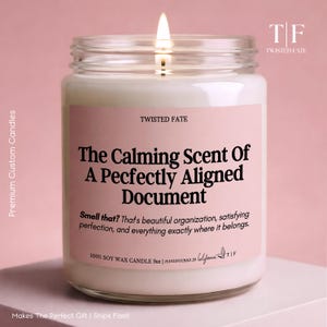 以下が含まれることがあります： 火のついた芯がある透明なガラス瓶に入った9オンスのソイワックスキャンドル。ラベルは薄いピンク色で、黒い文字で「TWISTED FATE, The Calming Scent Of A Pecfectly Aligned Document, Smell that? That's beautiful organization, satisfying perfection」と書かれています。