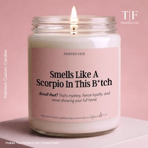 May include: A 9oz soy wax candle in a clear glass jar with a lit wick. The pink label features the text: TWISTED FATE, Smells Like A Scorpio In This B*tch, Smell that? That's mystery, fierce loyalty, and never showing your full hand. 100% SOY WAX CANDLE.