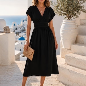 Puede incluir: Un vestido midi negro con escote en V, mangas cortas y una cintura ancha fruncida. El vestido tiene una falda fluida que cae por debajo de las rodillas. Un bolso de mano tejido de color tostado y sandalias de tiras marrones completan el conjunto.