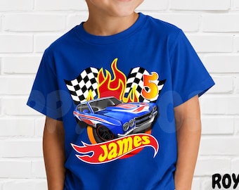 May include: A royal blue short-sleeve t-shirt featuring a graphic print of a blue race car, checkered flags, and orange flames. The design includes the number 5 in orange and the name James in yellow text within a red flame-shaped emblem.