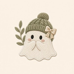 May include: An embroidered patch featuring a cream-colored ghost character wearing a sage green cable-knit beanie with a pom-pom and a small beige bow. The ghost has black oval eyes, pink cheeks, and is positioned next to a sage green leafy branch.
