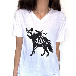 May include: White v-neck t-shirt with a black silhouette of a hyena printed on the front.