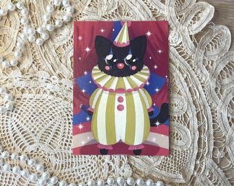 Peut inclure: Une impression d'art rectangulaire représentant un chat noir déguisé en clown. Le chat porte une collerette à volants rayée jaune et blanche, une combinaison assortie avec des détails roses, un petit chapeau pointu et du maquillage bleu.