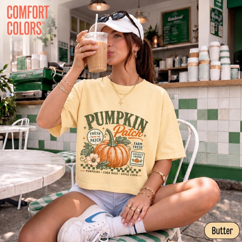 Op de afbeelding: Een lichtgeel T-shirt met korte mouwen en een grafische print van een pompoen met de tekst PUMPKIN Patch, Farm Fresh, Locally Grown, Pumpkins, Corn Maze en Apple Cider. Het shirt heeft een ronde hals en een relaxte pasvorm.
