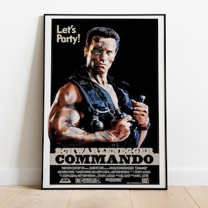May include: A framed movie poster for the film Commando featuring Arnold Schwarzenegger. The poster shows a muscular figure in a tactical vest holding grenades against a black background with the text Let's Party! and the movie title in bold.