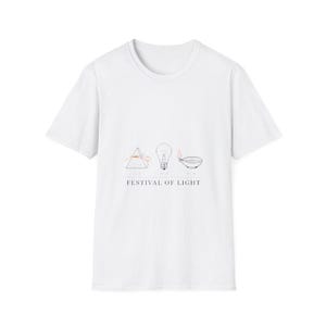 Puede incluir: Una camiseta blanca de manga corta con un gráfico central que muestra un prisma, una bombilla y una lámpara de aceite. Debajo de estos iconos, el texto FESTIVAL OF LIGHT aparece en una fuente negra sin remates.