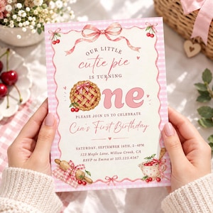 Puede incluir: Una tarjeta de invitación de cumpleaños rectangular con un borde de cuadros vichy rosa y blanco. El texto dice: Our little cutie pie is turning one. Please join us to celebrate Cia's First Birthday. Saturday, September 16th, 2-4pm, 123 Maple Lane, Willow Creek, CA. RSVP to Emma at 555.123.4567. Incluye ilustraciones de una tarta de cerezas, cerezas, un rodillo y cintas.
