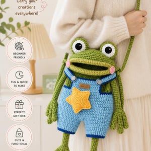 May include: A crochet frog bag featuring a green frog head with large white and black eyes, pink cheeks, and a wide mouth. The frog wears blue overalls with a yellow star patch on the front. The bag includes a long green strap for carrying.