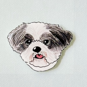 May include: A whimsical illustration of a Shih Tzu dog's face. The dog has black and white fur, large, expressive eyes, and a pink tongue. The artwork is outlined in black and set against a light background.