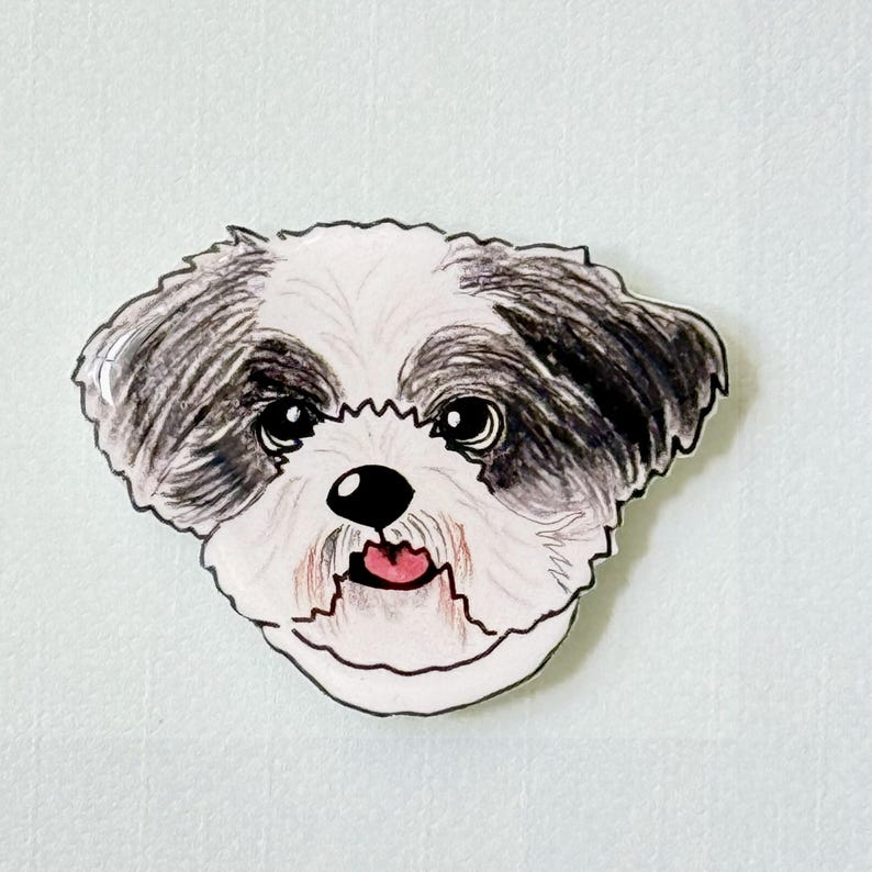May include: A whimsical illustration of a Shih Tzu dog's face. The dog has black and white fur, large, expressive eyes, and a pink tongue. The artwork is outlined in black and set against a light background.