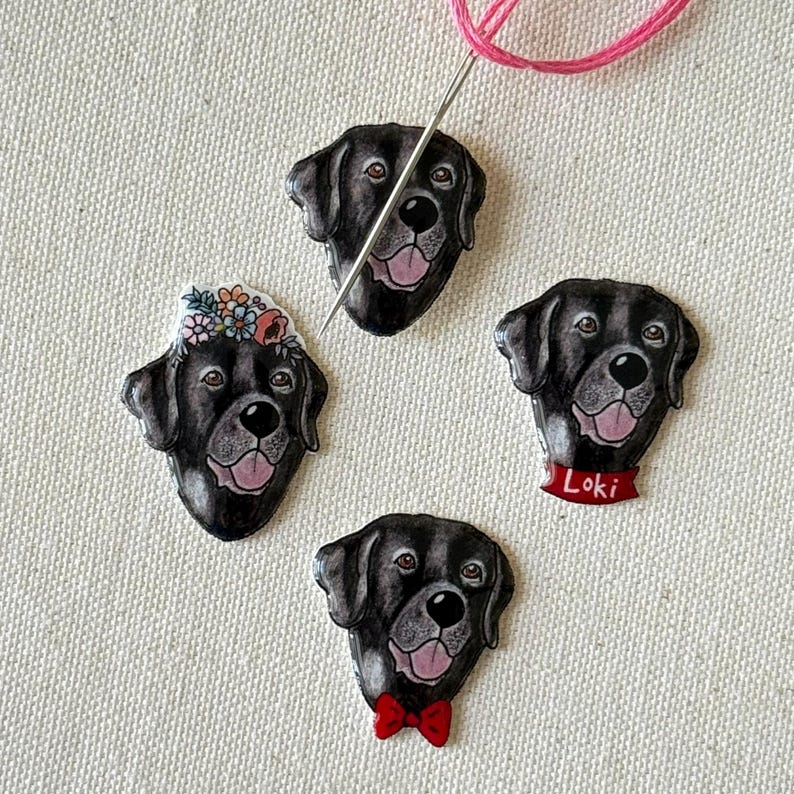 Puede incluir: Cuatro pines de cabeza de perro Labrador Retriever negro con diferentes dise&ntilde;os. Un pin tiene una corona floral, uno tiene una pajarita roja, uno tiene un collar rojo con el nombre "Loki" y uno no tiene adornos.