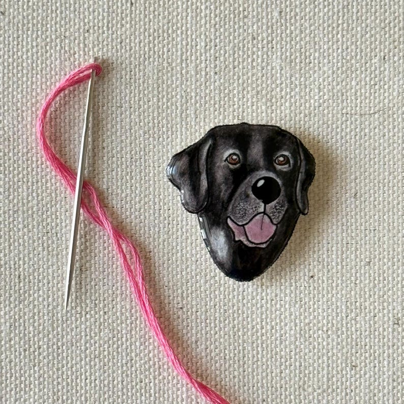 Puede incluir: Una ilustraci&oacute;n de la cabeza de un perro Labrador Retriever negro, con ojos marrones y una lengua rosa. La ilustraci&oacute;n est&aacute; sobre un fondo blanco.