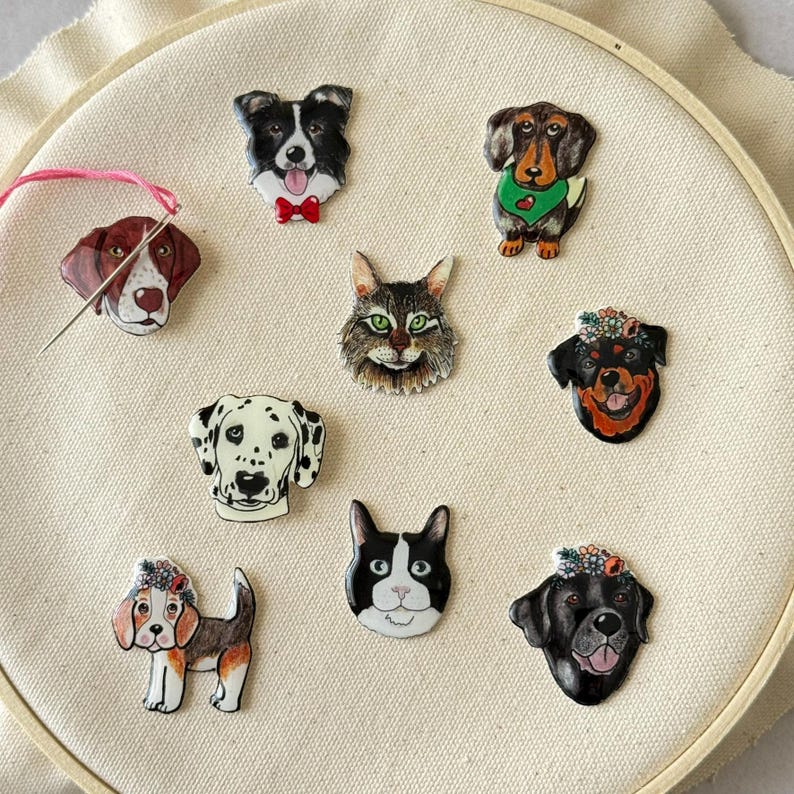 Puede incluir: Ocho pines de animales diferentes, incluyendo un d&aacute;lmata blanco y negro, un gato blanco y negro, un perro blanco y negro con una corona de flores, un labrador negro con una corona de flores, un perro marr&oacute;n y blanco con una corona de flores, un border collie blanco y negro, un dachshund marr&oacute;n y blanco y un pointer marr&oacute;n y blanco.