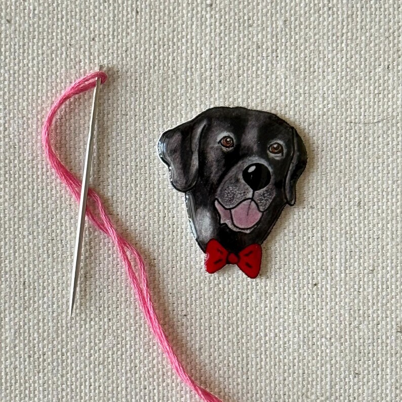 Puede incluir: Una cabeza de perro Labrador Retriever negro con una pajarita roja, pintada sobre un fondo blanco.