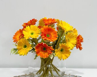 オレンジイエローのガーベラアレンジメント：ガラスの花瓶に入った造花