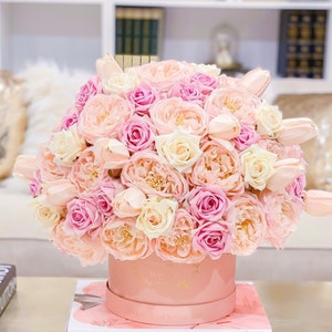 Puede incluir: Un arreglo floral de rosas y tulipanes en rosa y blanco en una caja de sombrero rosa.