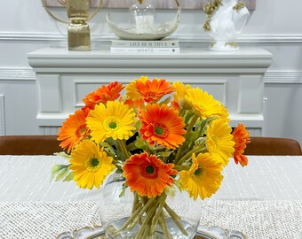 オレンジイエローのガーベラアレンジメント：ガラスの花瓶に入った造花