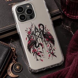 May include: A clear smartphone case featuring a graphic illustration of two black flamingos with pink accents, surrounded by thorny branches and pink flowers, centered around a geometric black line design on the back of the device.