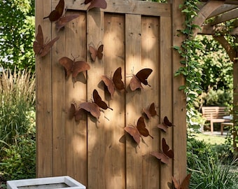 May include: A collection of twelve brown metal butterfly wall decorations arranged in a scattered pattern across a vertical wooden fence panel. Each butterfly features a flat, cutout design with wings angled to create a dimensional effect.