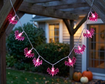 May include: A string of decorative lights featuring translucent pink bat-shaped covers. The lights are connected by a thin, clear wire and are illuminated, casting a bright pink glow from each individual bat figure along the entire length.