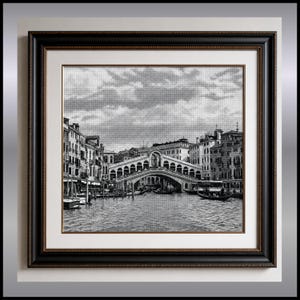 Peut inclure: Une broderie au point de croix en noir et blanc représentant le pont du Rialto à Venise, en Italie. La scène montre le pont en pierre arqué au-dessus d'un canal avec des gondoles et des bâtiments environnants, le tout dans un cadre en bois sombre.